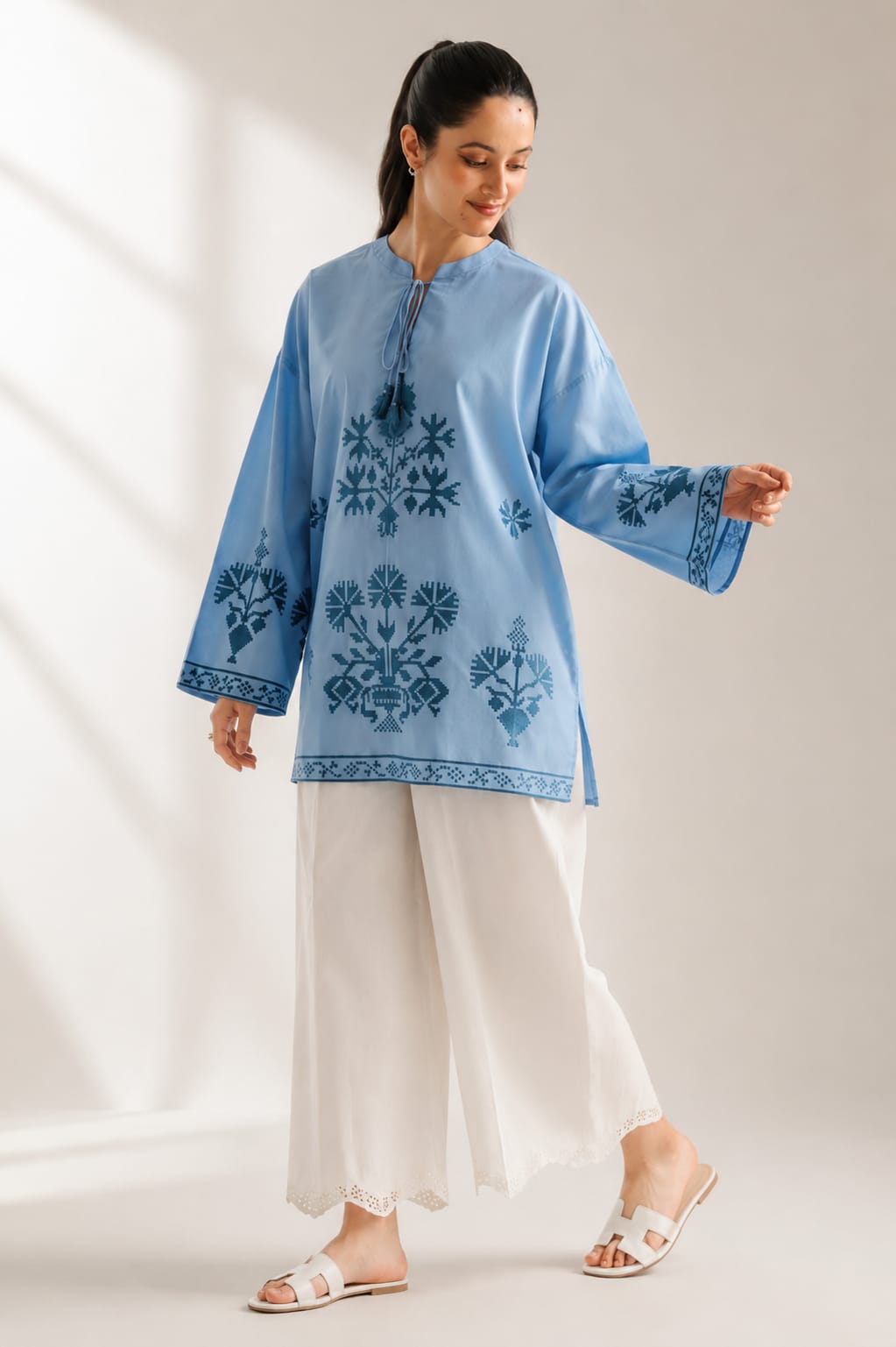 Close-up of intricate embroidery on sky blue tunic neckline